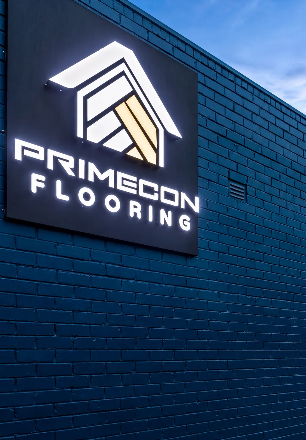 Primecon Flooring shopfront at 2/1386 Toorak Road, Camberwell, with the lit sign on the navy brick wall